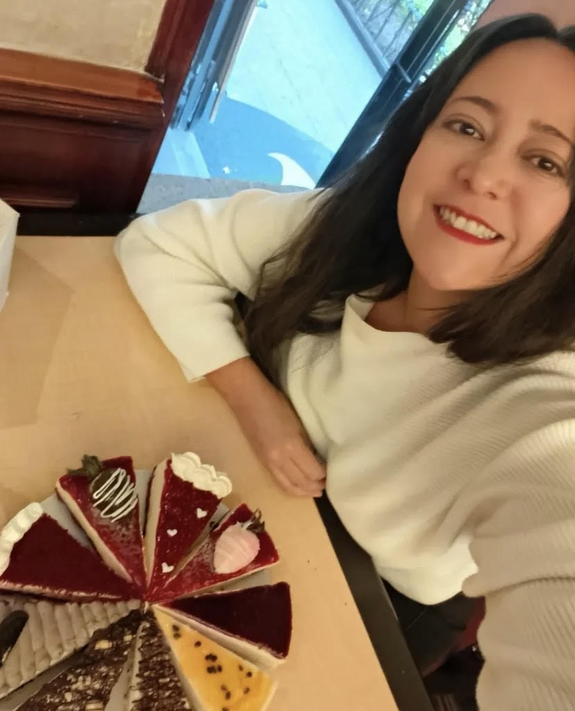 Dueña de la pastelería sonriendo junto a sus pasteles